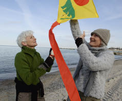 Two mature women flying a kite at Baltic Sea beach